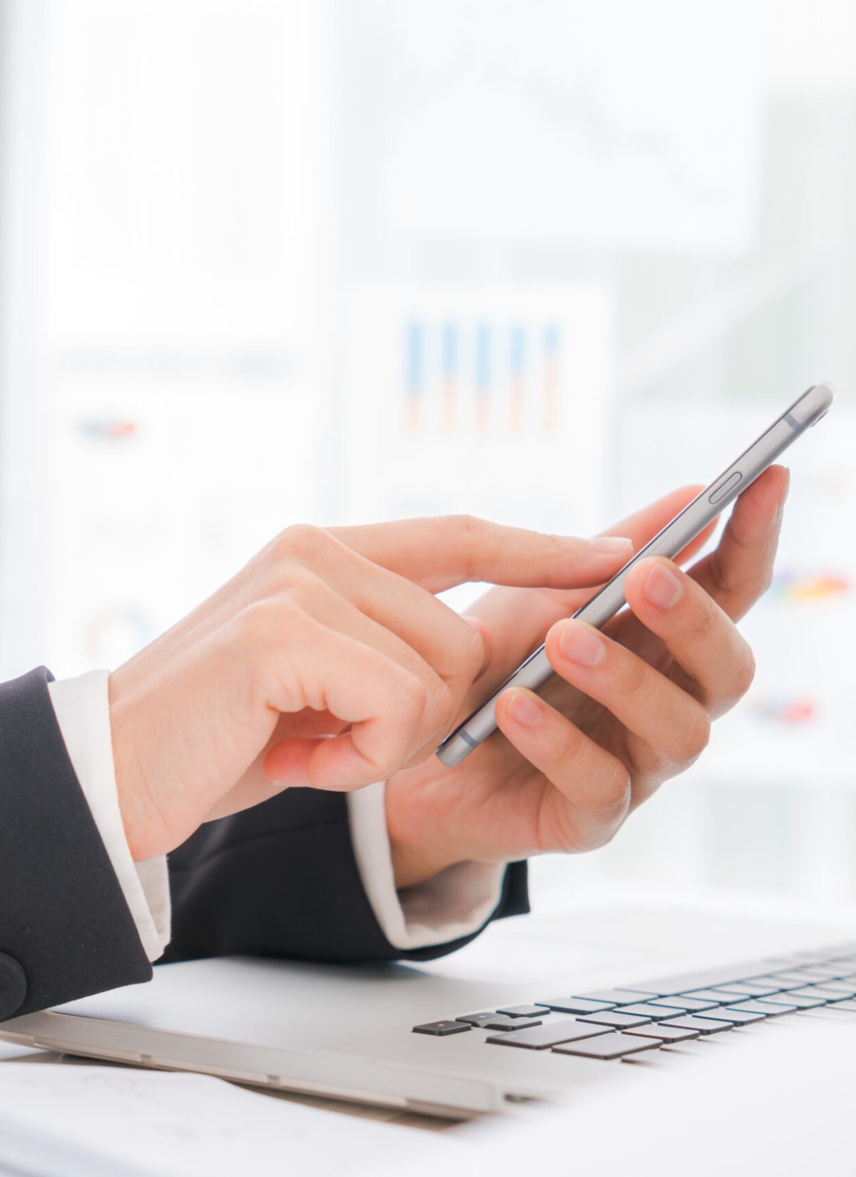 Closeup of business woman hand typing on laptop keyboard with  mobile phone